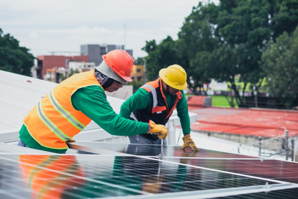 Solar Panel Cost in the Philippines 2026: How Much Does Home Solar Installation Cost? Two workers installing rooftop solar panels safely equipped with PPE and tools.